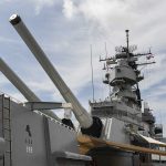 Close up of a battleship's naval guns and superstructure against a cloudy sky