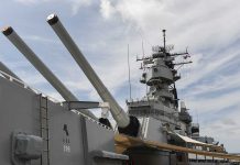 Close up of a battleship's naval guns and superstructure against a cloudy sky
