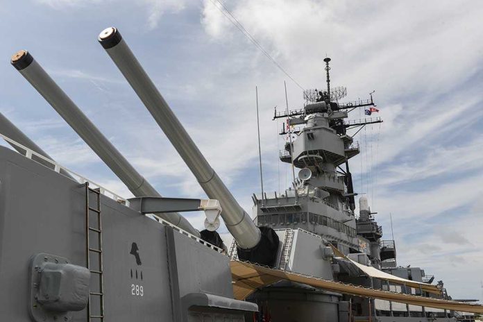 Close up of a battleship's naval guns and superstructure against a cloudy sky