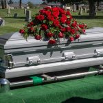 Silver casket with rose bouquet in a cemetery.