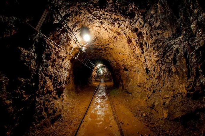 shutterstock_130135697.jpg Dimly lit underground tunnel with rail tracks and rocky walls