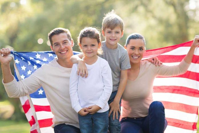 shutterstock_193297637.jpg A family of four posing outdoors with an American flag