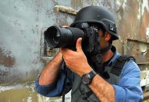 A photographer in military gear aiming a camera