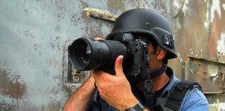 A photographer in military gear aiming a camera