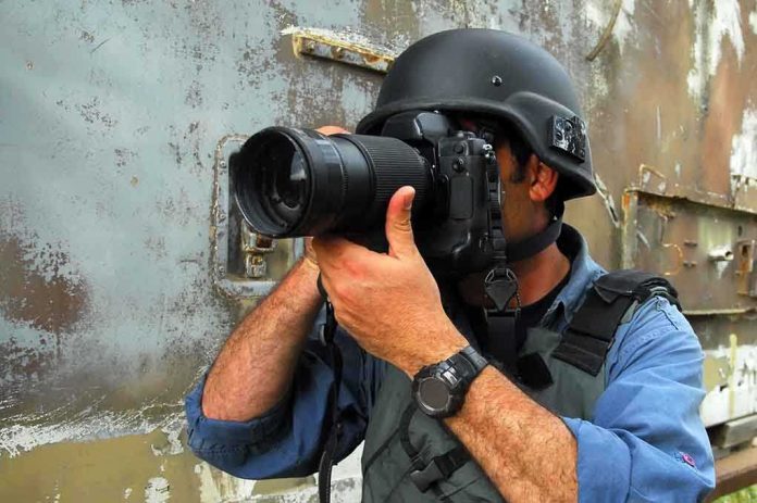 A photographer in military gear aiming a camera