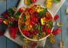 A bowl filled with colorful gummy bears surrounded by scattered candies