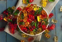 A bowl filled with colorful gummy bears surrounded by scattered candies