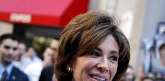 A smiling woman engaging with a crowd at a political event
