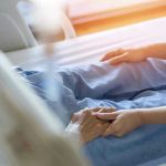 Hospital patient holding visitors hand reassuringly