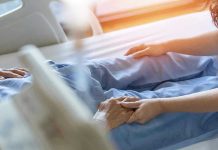 Hospital patient holding visitors hand reassuringly