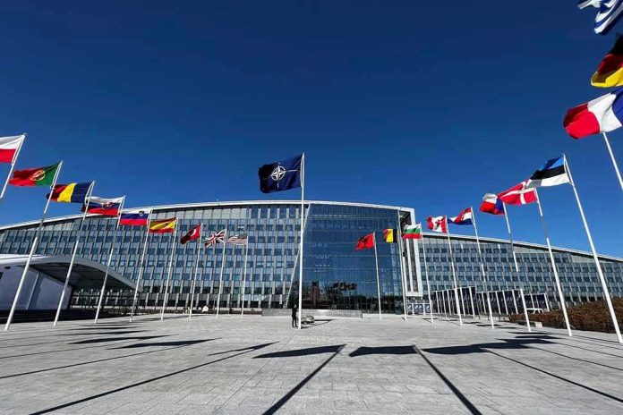 2284120437 Flags outside NATO headquarters building under clear blue sky