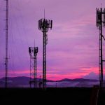 Cell towers against a purple sunset sky
