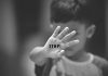 Child holding up hand with STOP! written on palm