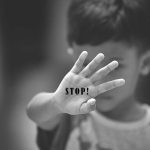 Child holding up hand with STOP! written on palm