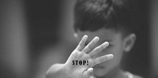 Child holding up hand with STOP! written on palm