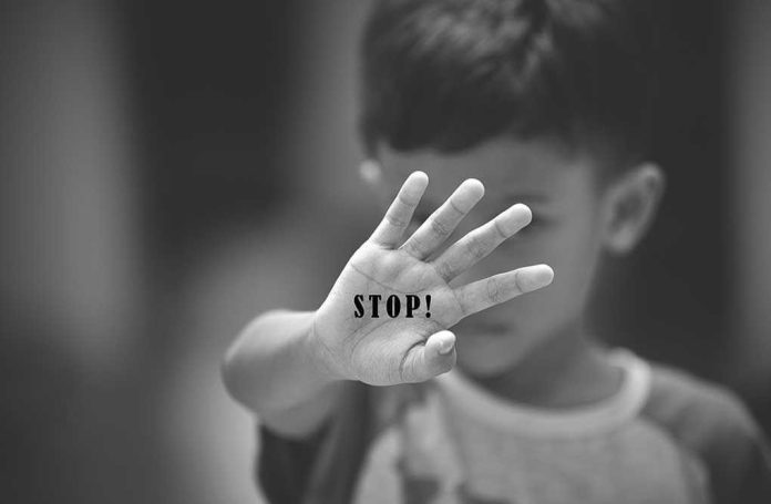 Child holding up hand with STOP! written on palm