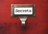 A label holder on a wooden surface with the word Secrets displayed