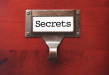 A label holder on a wooden surface with the word Secrets displayed