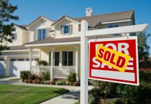 A house with a Sold sign in the front yard