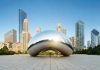 Cloud Gate sculpture with skyline of skyscrapers behind it