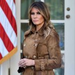 Melania REVOLTS Against Trump’s Shocking White House Plan Woman in brown coat beside American flag