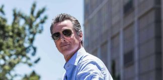 Newsom’s Biblical Assault on Republicans BACKFIRES Man in sunglasses wearing a blue button up shirt