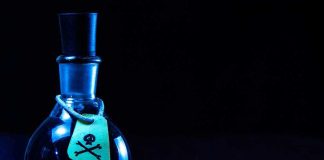 Dark bottle with skull and crossbones label on table