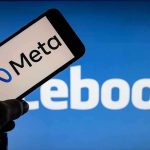 Meta on phone screen Facebook in background