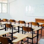 WOKE Mx Title Battle Erupts in Schools Empty classroom with desks chairs and whiteboard