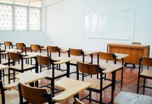 WOKE Mx Title Battle Erupts in Schools Empty classroom with desks chairs and whiteboard