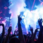 KISS Icon Collapses! Fans Fear the Worst Crowd at a concert with hands raised and smoke effects in the background