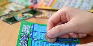 A person scratching off a bingo lottery ticket with a coin