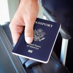 Trump Orders AXE Nonbinary Passports A person holding a United States passport next to a suitcase