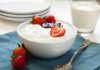 A bowl of creamy dessert topped with fresh strawberries and a drizzle of jam