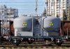 A railway tank car with a nuclear warning symbol parked on tracks near urban buildings