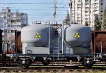 Private Firms Get Plutonium Access – Outrage Erupts A railway tank car with a nuclear warning symbol parked on tracks near urban buildings