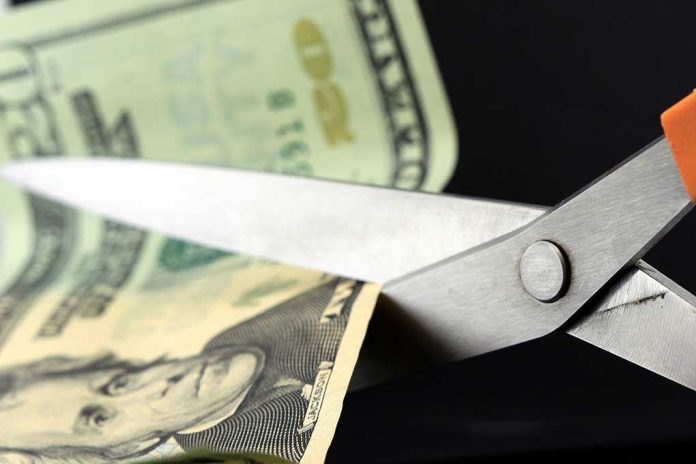 shutterstock_96493580.jpg Scissors cutting a dollar bill against a dark background