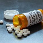 Open pill bottle with white tablets spilled out.