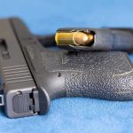 Handgun on blue fabric with visible bullet cartridge