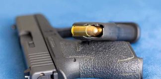 Armed Intruder Down—Police Storm Home Handgun on blue fabric with visible bullet cartridge