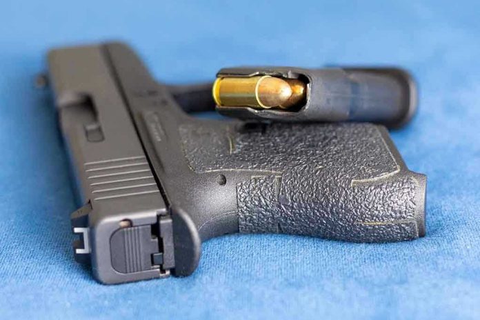 2159542825 Handgun on blue fabric with visible bullet cartridge