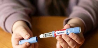 Hands holding an Ozempic injection pen.