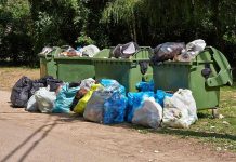SHOCKING Discovery — Child’s Body Found in Bin Overflowing garbage bins with bags on the ground.