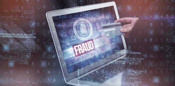 665585107 Person holding credit card near laptop displaying Fraud