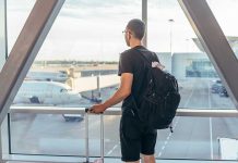 A traveler looking out of an airport window at parked airplanes