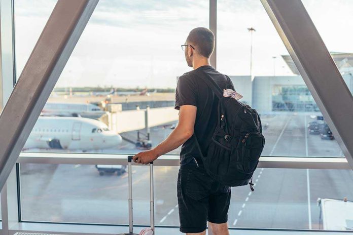 A traveler looking out of an airport window at parked airplanes