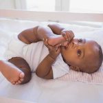 Community Outraged: Demand for Justice in Infant Death A playful baby lying in a crib, holding their feet