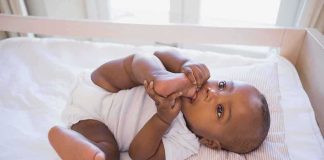 A playful baby lying in a crib, holding their feet