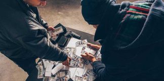 Food Supply UNDER ATTACK From New Threat Two individuals handling stacks of money on a table.
