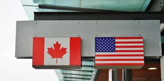 Canada’s $108K Penalty For Staying Alive Canadian and American flags displayed at a border crossing